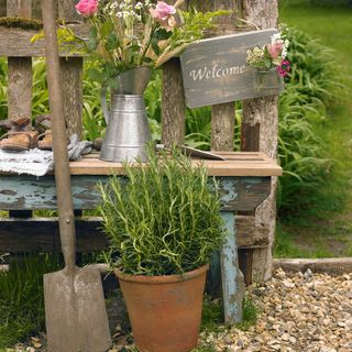 Garden bench with rosemary plant and a welcome sign