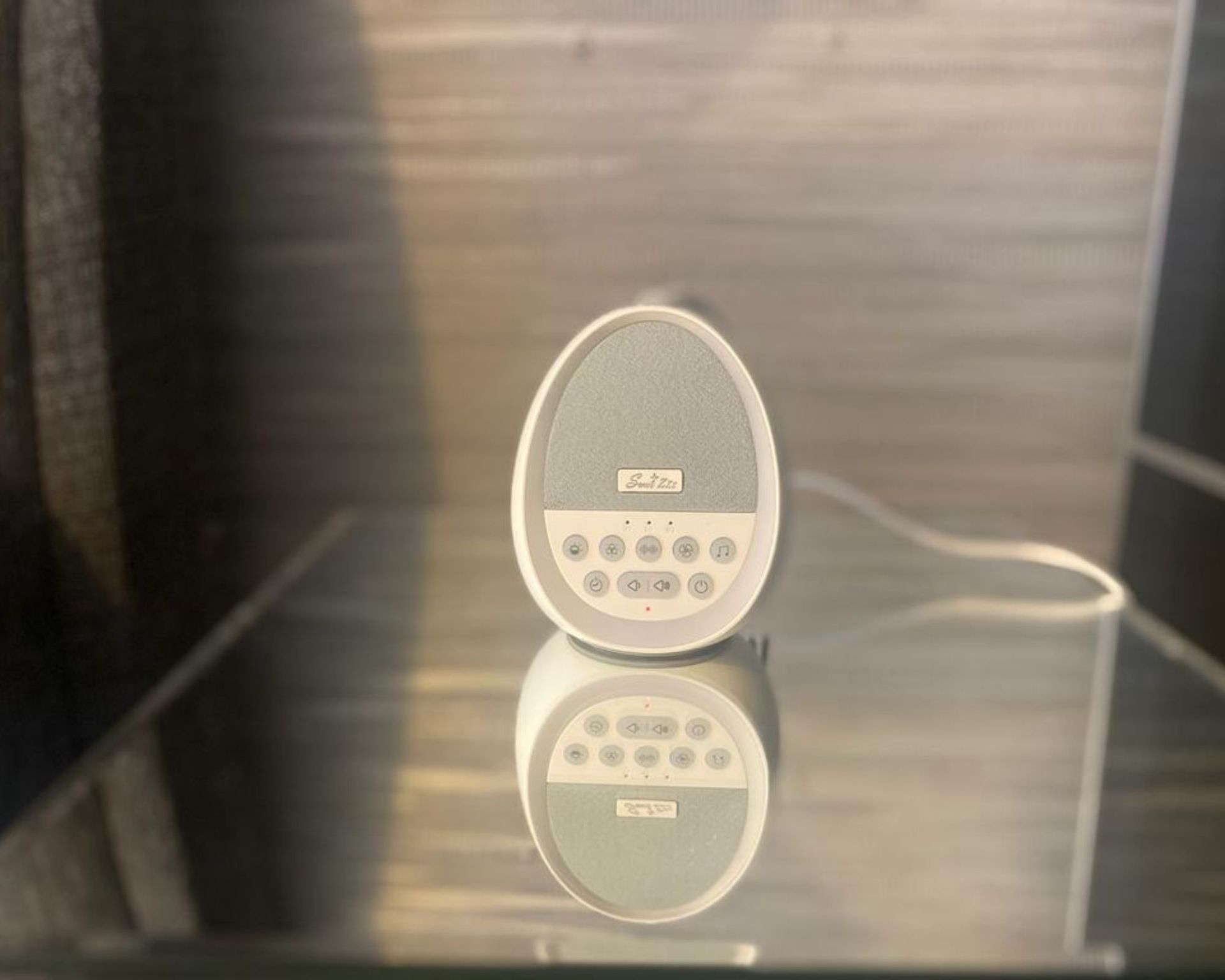 Mesin Sweet Zzz dengan white noise di meja samping tempat tidur bercermin