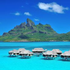 blue sea with huts over water and mountain background