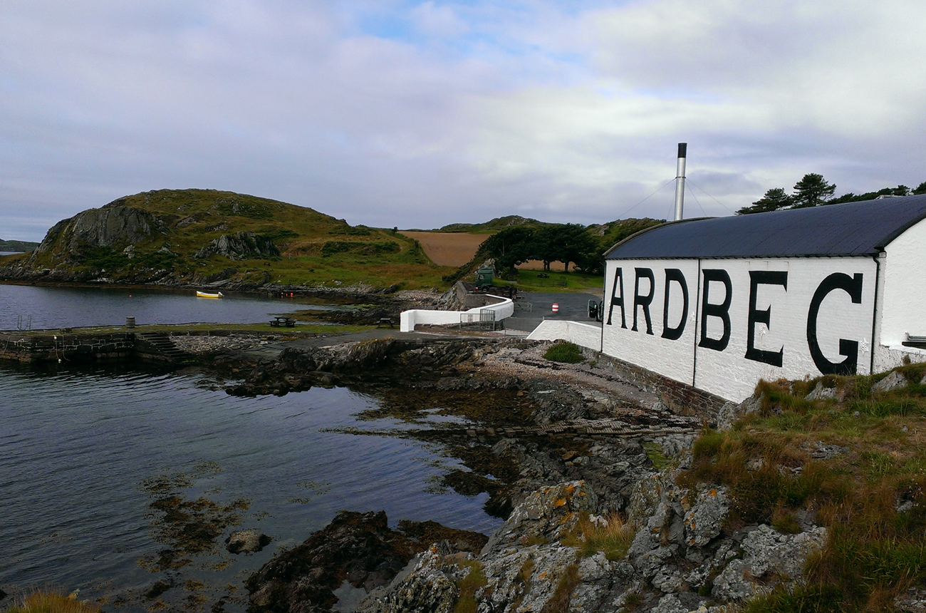 A whisky distillery building by the sea with hills and sky