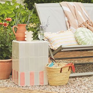 DIY tiled side table in patio area next to deck chair and handbag in garden