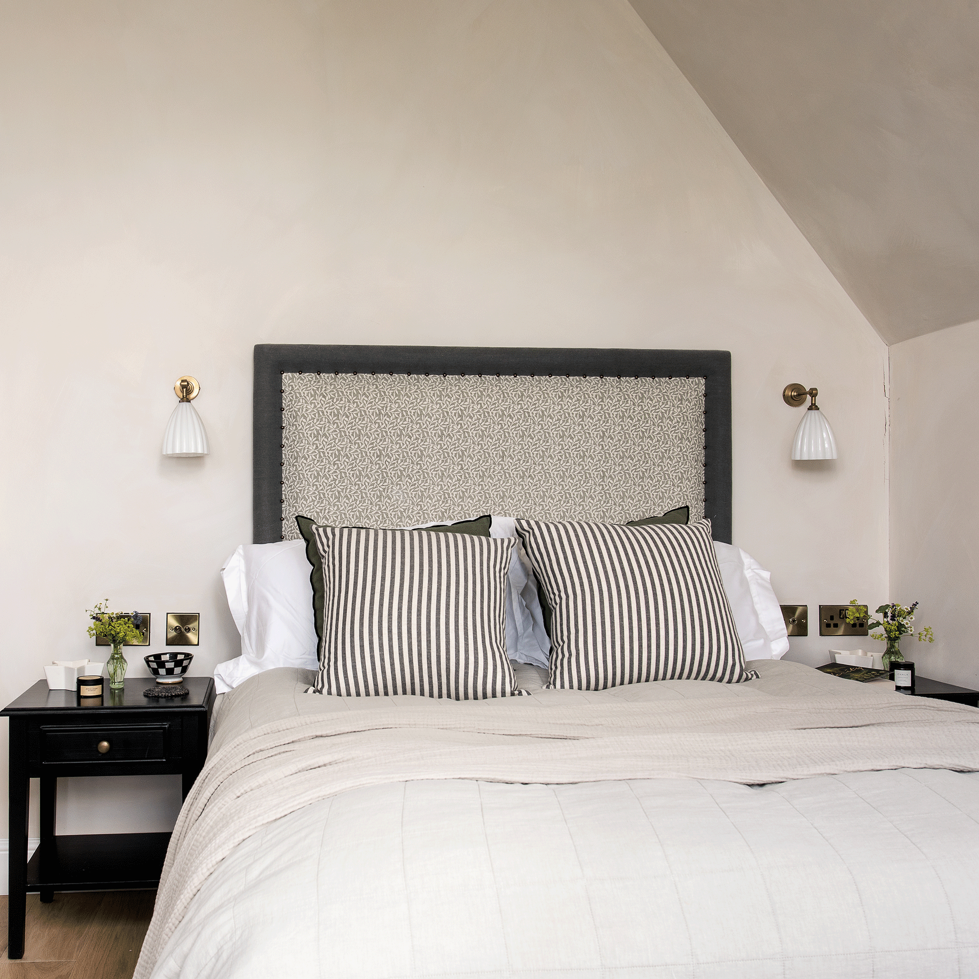 Green bed in a plaster colour room with white ceramic lamps