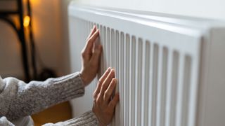 Woman placed both hands on a radiator to feel the heat
