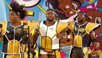 Xavier Woods, Big E, and Kofi Kingston at WrestleMania in Dragon Ball inspired Saiyan armor. Kofi and Xavier are wearing black suits, and Big E is wearing white in the center. 