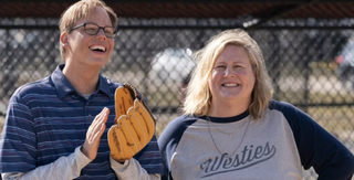 Bridget Everett and Jeff Hiller smiling on a baseball pitch