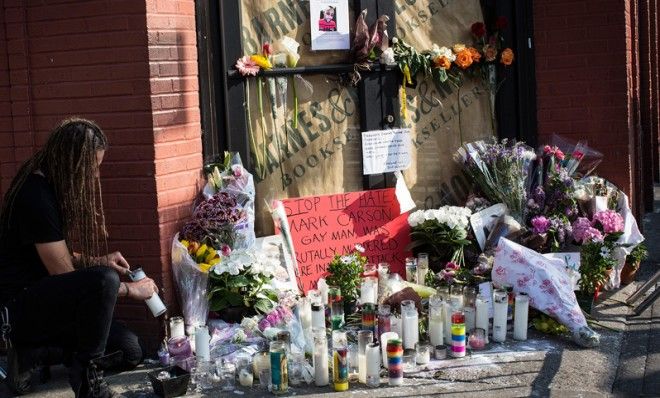 A man lights a candle at the shrine for Mark Carson during the Rally Against Hate on May 20.