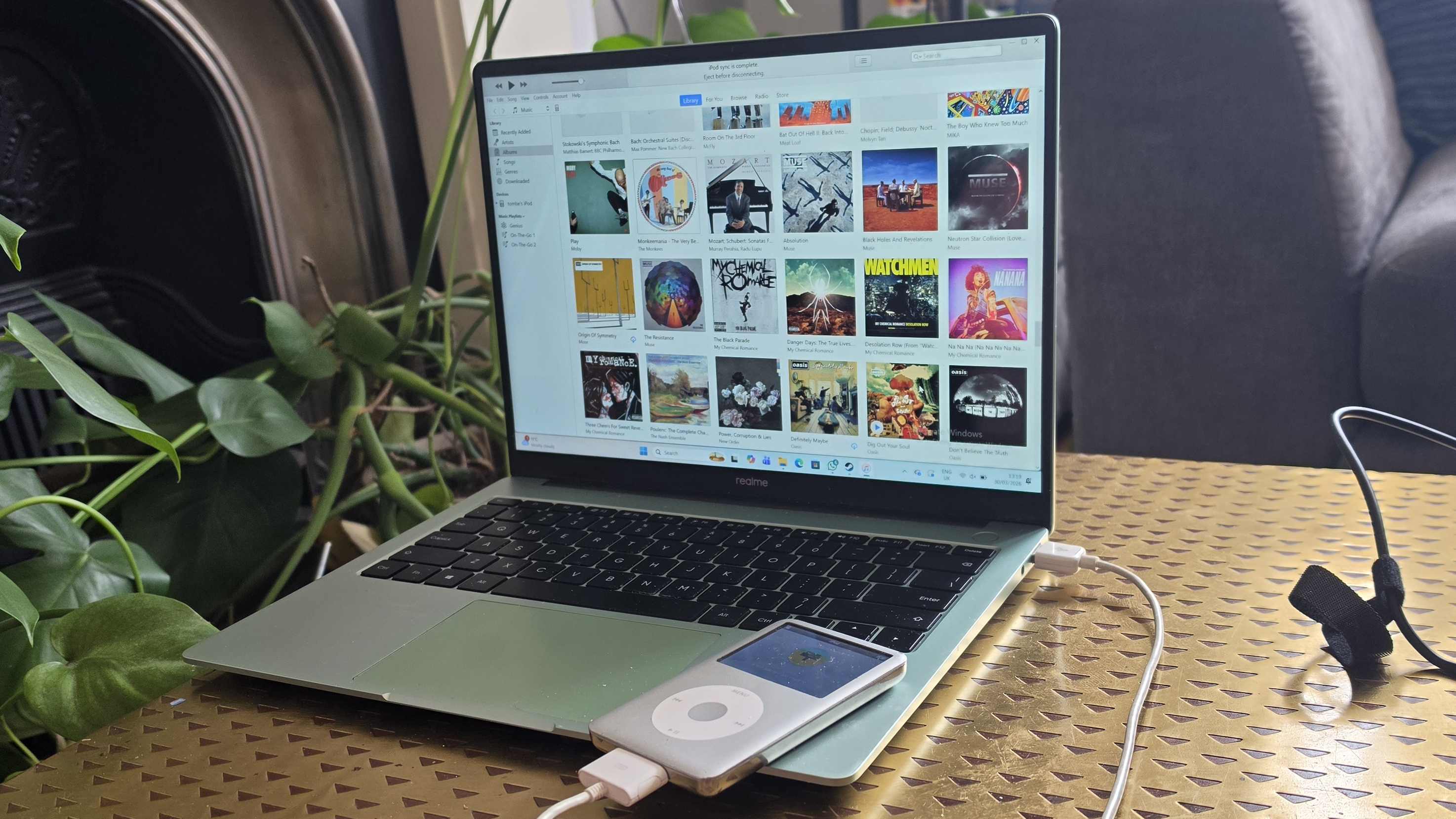 The iPod Classic connected to a green Realme laptop, showing iTunes.