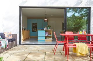patio with red dining set and sliding glass doors looking into a blue kitchen
