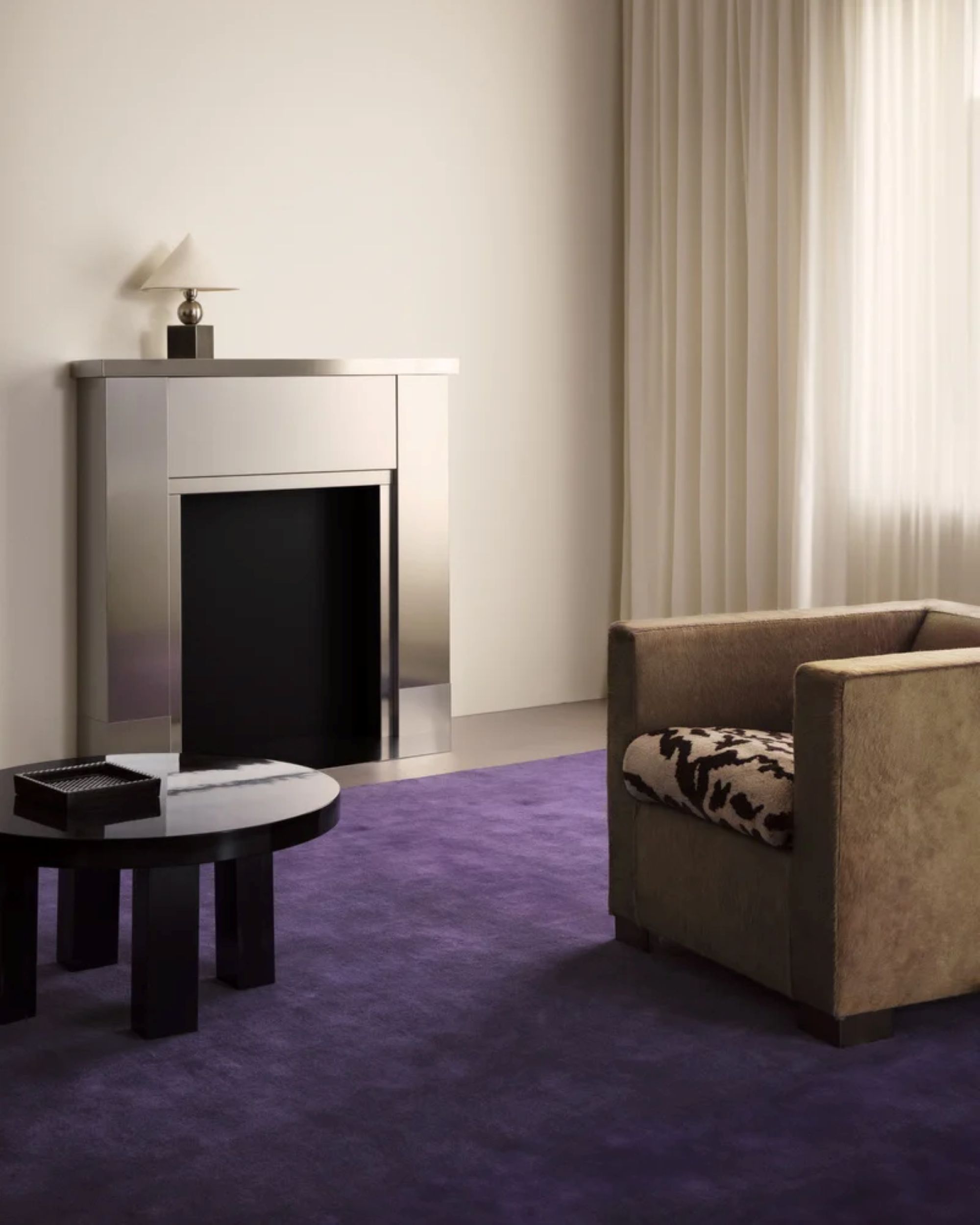 living room with a purple rug, camel arm chair, and chrome fireplace