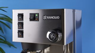 Rancilio Silvia in Stainless steel on a wooden worktop with a blue wall in the background.