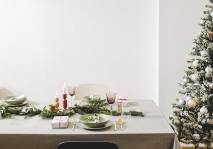 A dining table with modern christmas decor next to a christmas tree