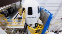 A white Blue Origin crew rocket RSS Karman Line surrounded by blue and yellow scaffolding ahead of its first launch.