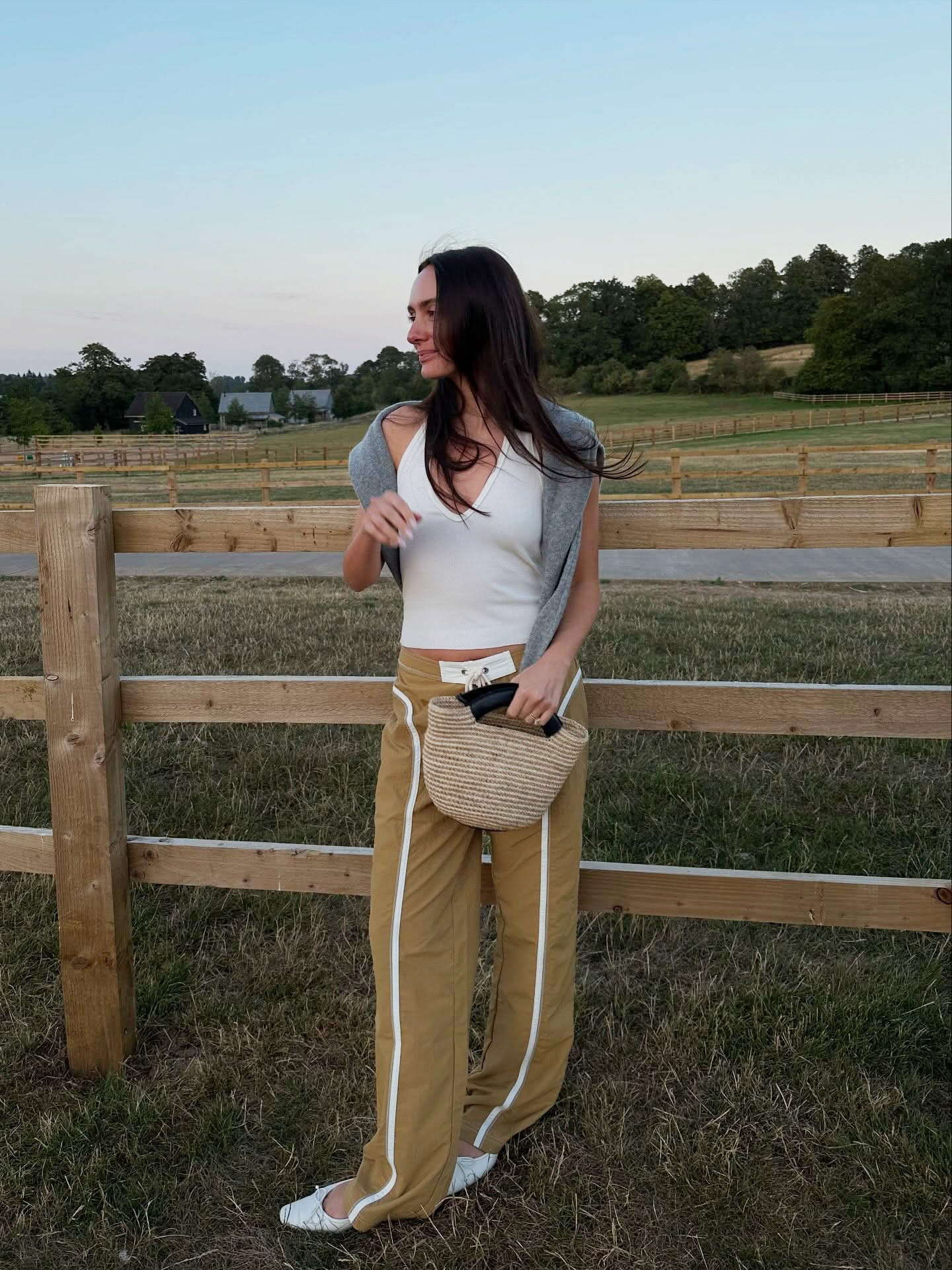 Influencer wearing dark beige pants with a white tank and white flats