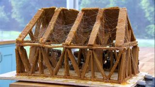 A skeletal gingerbread house looks on the edge of collapse