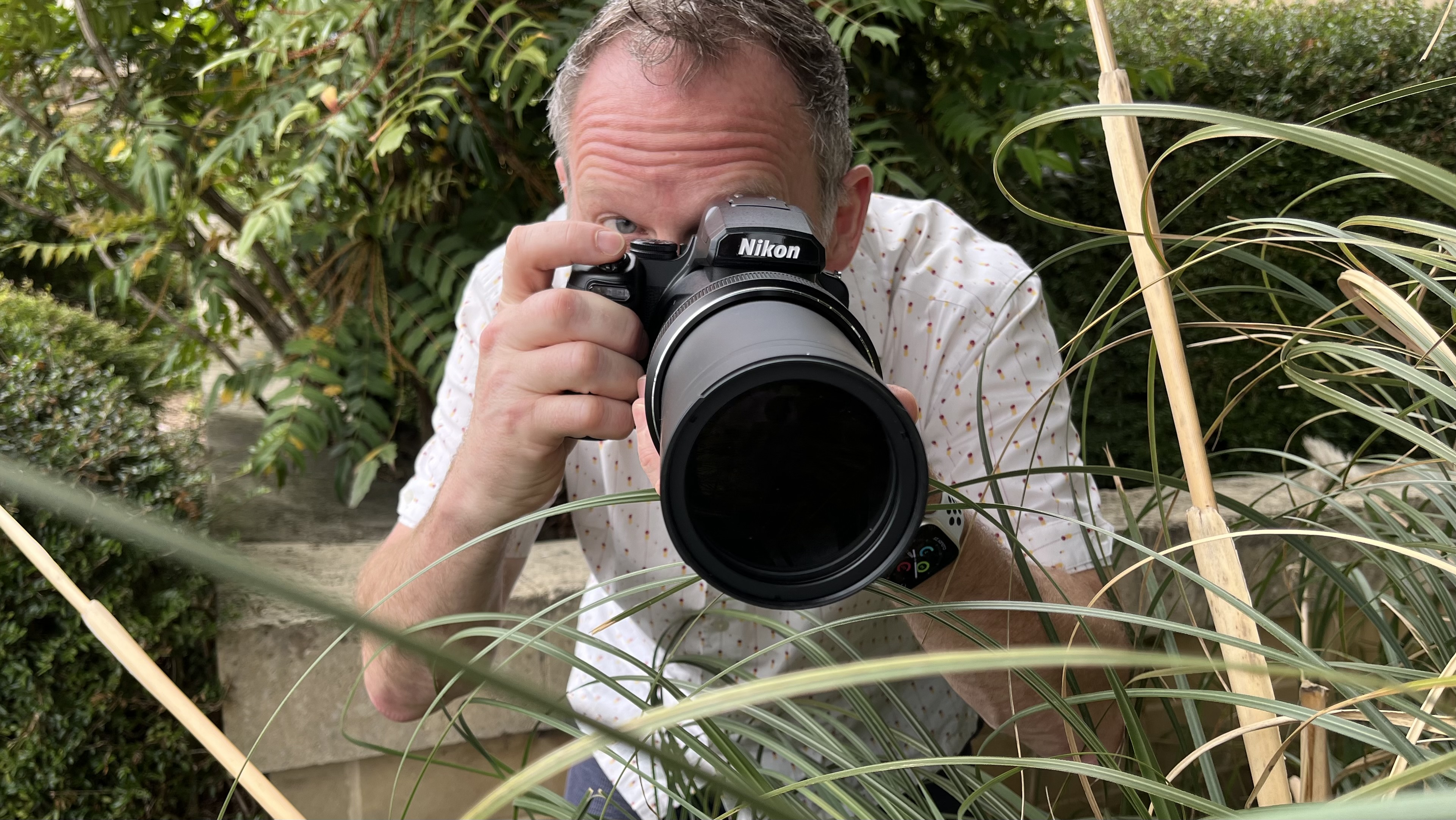 Nikon Coolpix P1100 lifestyle image of Adam Waring shooting through grasses 
