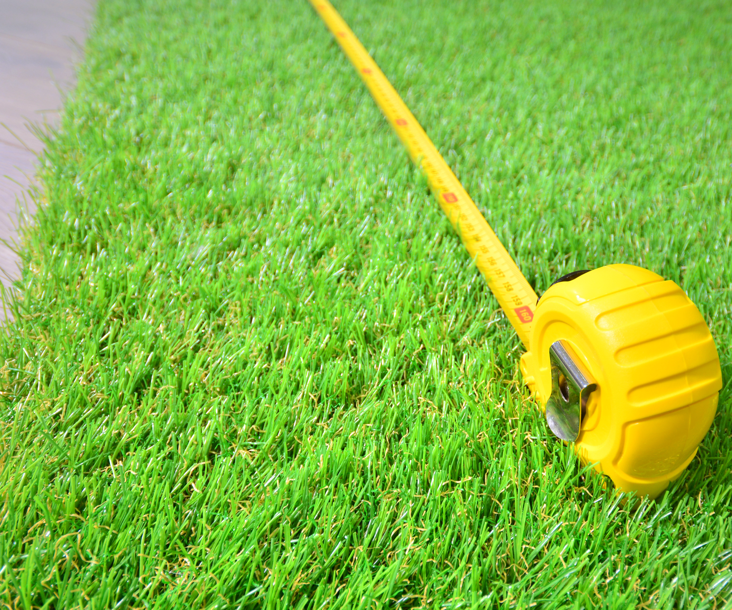 Artificial turf and measure tape lie on the laminate floor