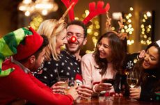 Group Of Friends Enjoying Christmas Drinks In Bar Smiling Wearing Christmas Hats