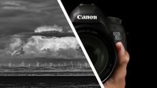 Monochrome image of a distant wind farm alongside a Canon DSLR camera in the hand with black background