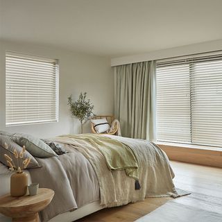 Neutral bedroom with wooden flooring and venetian blinds