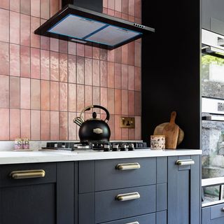black kitchen cabinets with pink tiles and hob