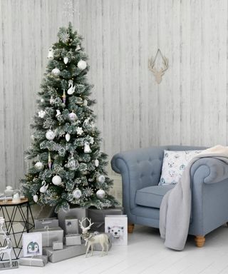 Arctic Chic: Christmas tree decorated with white decorations with white wrapped presents next to light blue armchair
