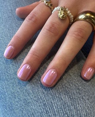 A woman's hands are painted with light pink nails.