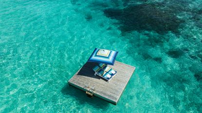 Blue missoni patterned parasol and lounger on blue sea at One & Only Reethi Rah Maldives resort
