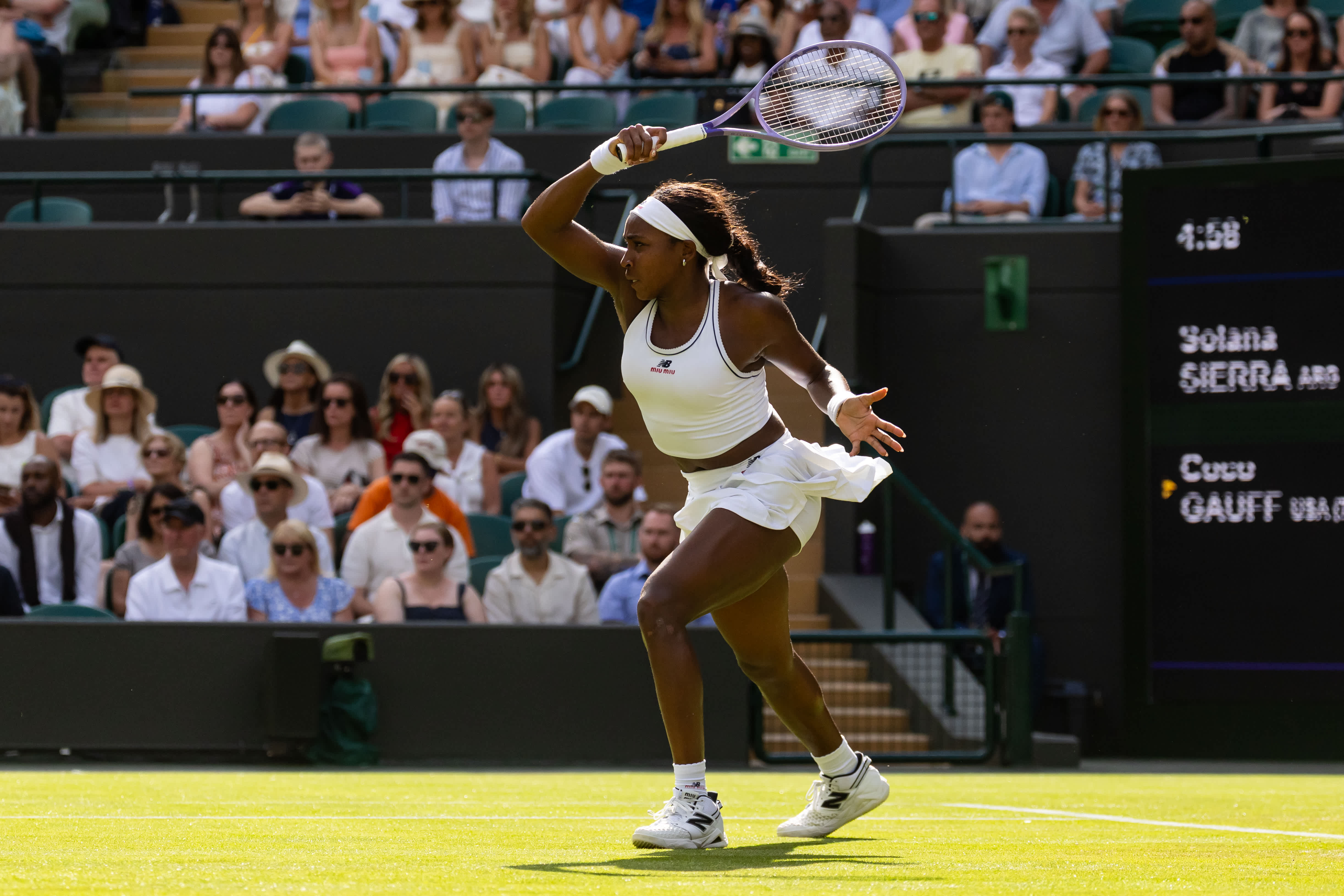 Coco Gauff playing at Wimbledon wearing a Miu Miu x New Balance two-piece set.