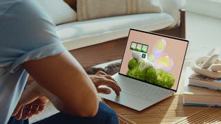 A man using a Dell XPS 13 while it sits on a coffee table.