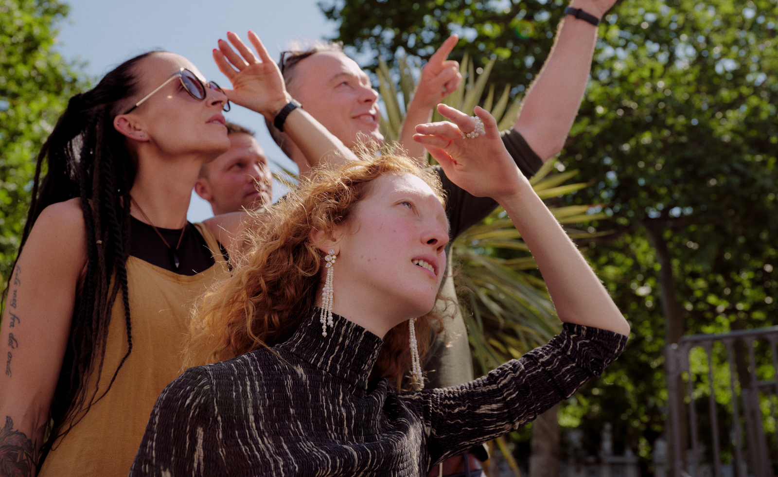women shading eyes from sun and looking up, wearing jewellery