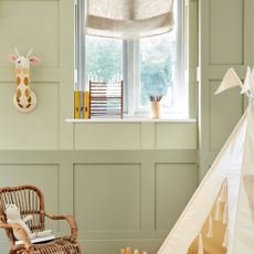 Two tone wall with light and dark sage green with window, behind white tent and wicker chair