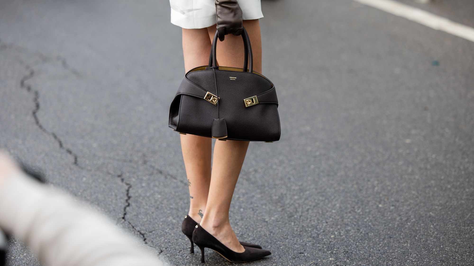 a street style star carrying a ferragamo hug bag during milan fashion week