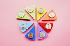 Pie chart made of colorful building blocks and stacks of American Dollar coins on pink background 