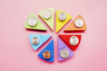 Pie chart made of colorful building blocks and stacks of American Dollar coins on pink background 