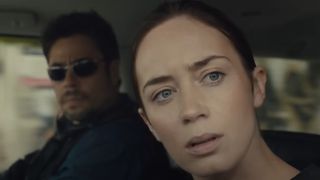 Emily Blunt and Benicio del Toro looking out a window in Sicario.