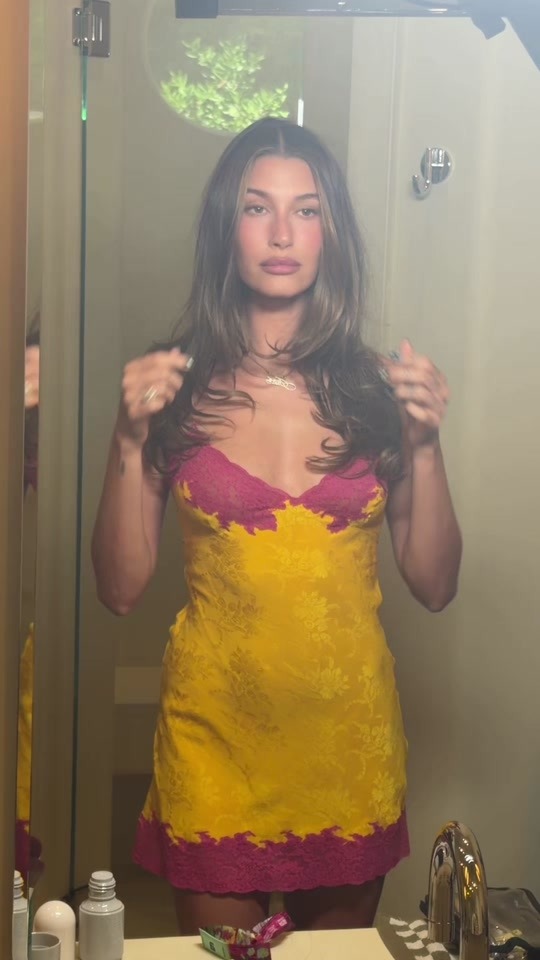 Hailey Bieber at coachella 2026, wearing a yellow and pink minidress with a long haircut with waterfall layers