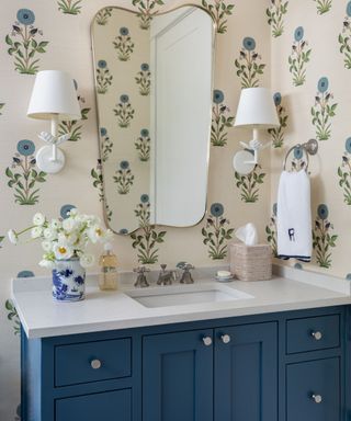 blue floral wallpaper with navy blue vanity storage and plaster flower wall sconces
