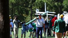 Bryson DeChambeau carries a sign away at The Masters