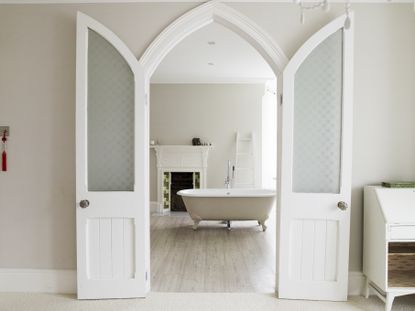 View through a doorway to a bathroom with a free standing bath with walls painted greige