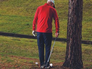 Golf Monthly Top 50 Coach Barney Puttick playing a shot backwards to escape tree trouble