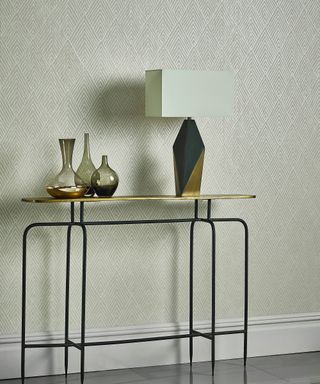 How to wallpaper a room, demonstrated in a light color scheme with beige patterned wallpaper and slim metal console table.