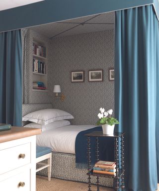 Blue nook bed with wallpaper and drapes across