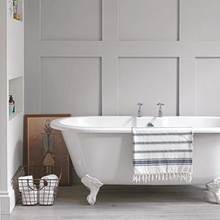 bathroom with grey wall white bathtub and grey wooden flooring