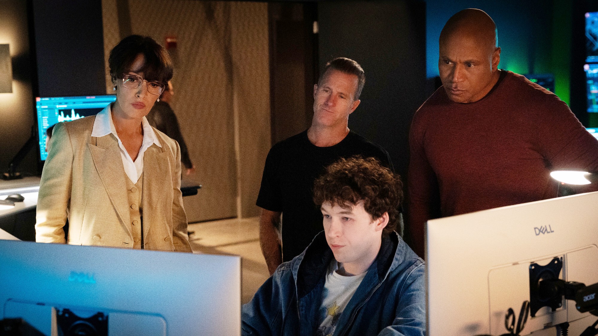 The NCIS: New York team all huddled around a computer. 