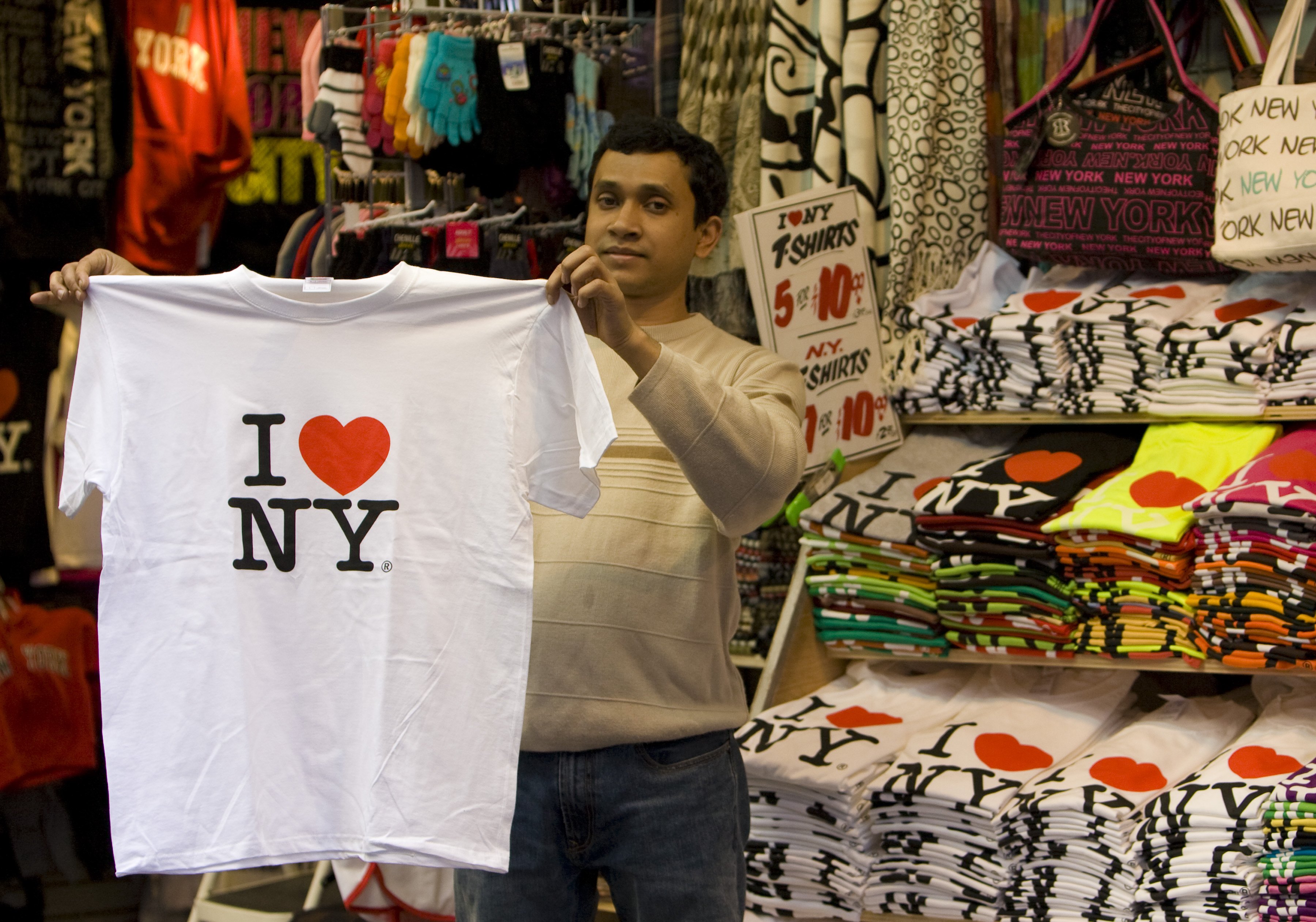 A street vendor on 7th Avenue near Broadway and Times Square holds up a "I Love New York" in this 2009 New York, NY, early afternoon cityscape photo.
