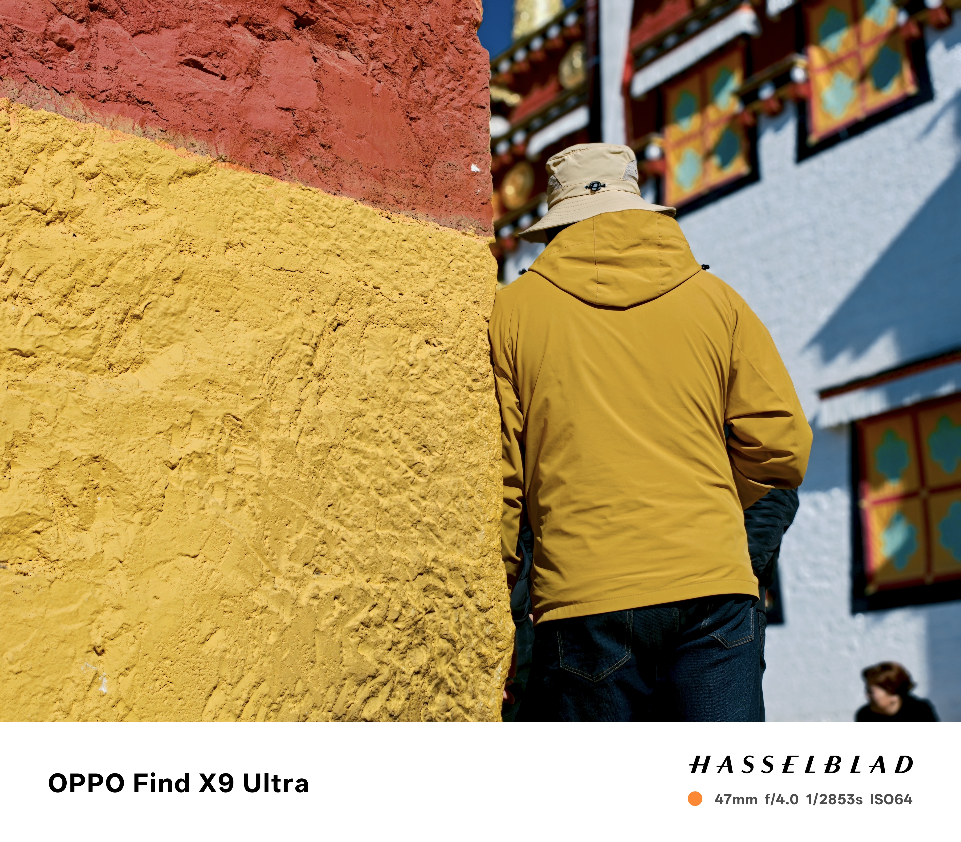 Man in a yellow jacked, leaning against a yellow-painted wall