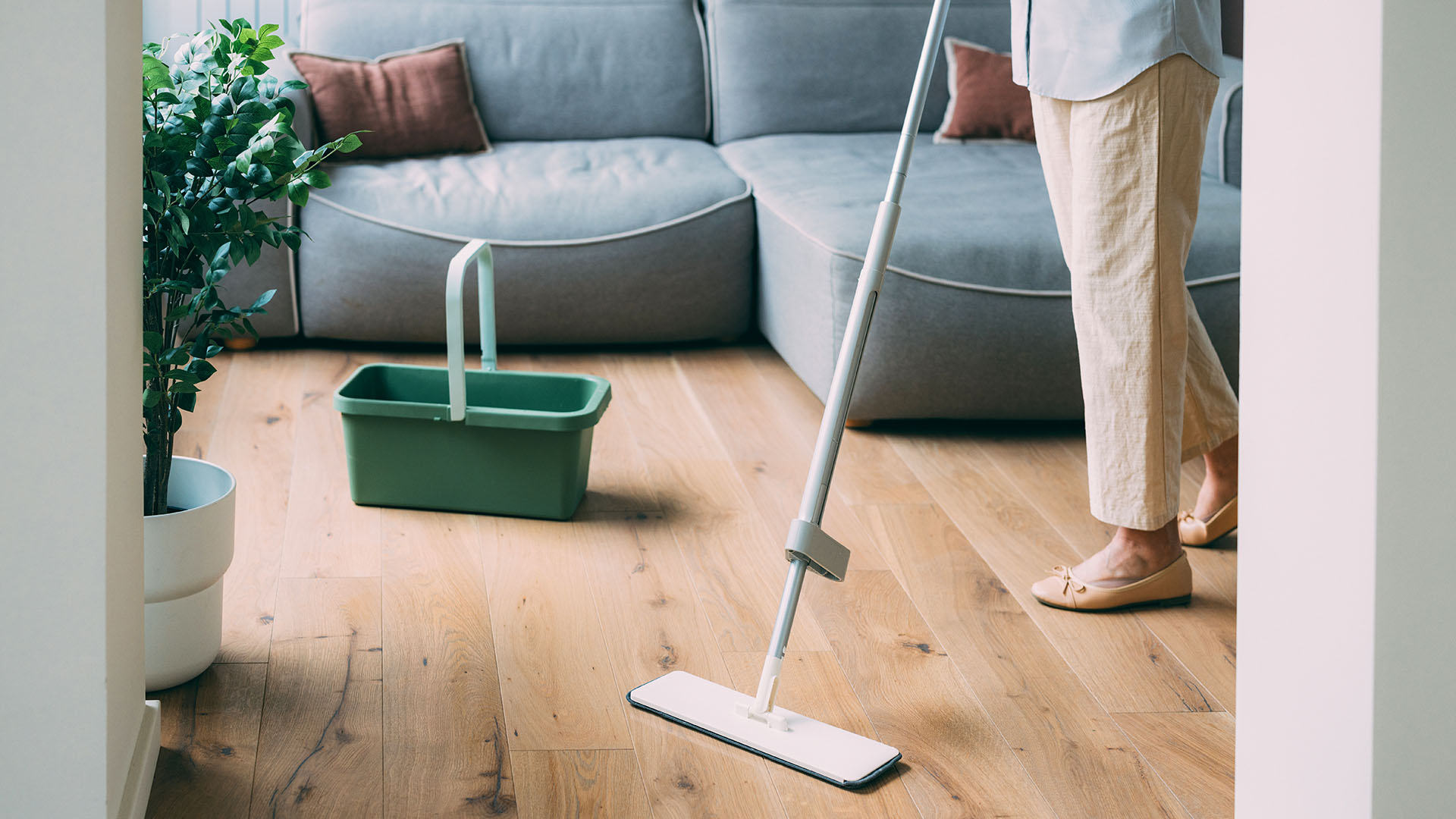 Woman cleaning a hardwood floor with a flat mop