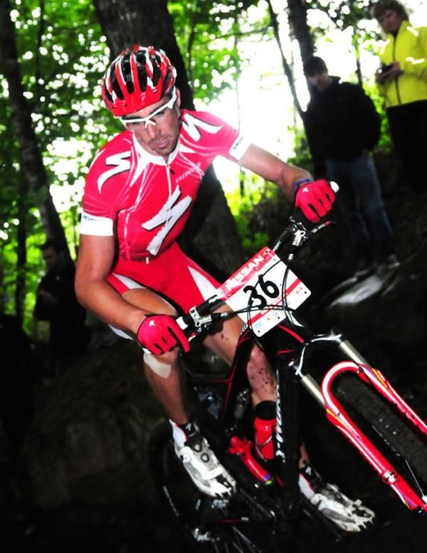 Todd Wells (Specialized) riding through the dark, rainy woods.