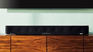 Sennheiser Ambeo Soundbar Max on a wooden entertainment unit.