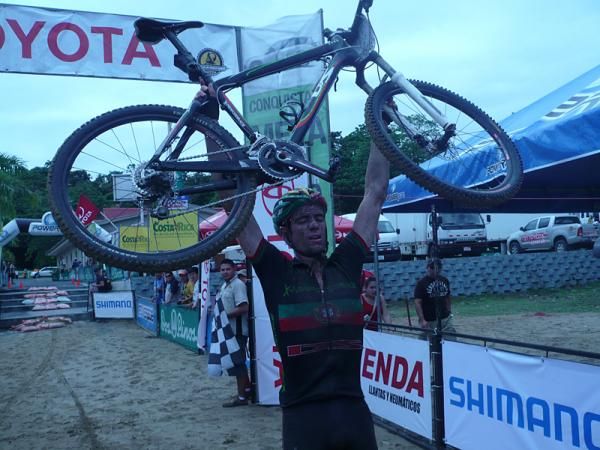Stage winner Luis Leao Pinto holds his bike in the air in celebration.